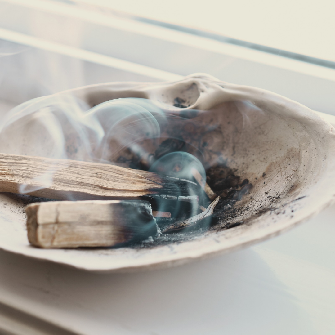 Nestled in an abalone shell are some energy cleansing tools. A gently smouldering wand of palo santo alongside a Quartz crystal to not only further cleanse but to raise the vibrational frequency