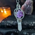 Crystal pendulum with Amethyst merkabah and clear crystal on a dark background with candles