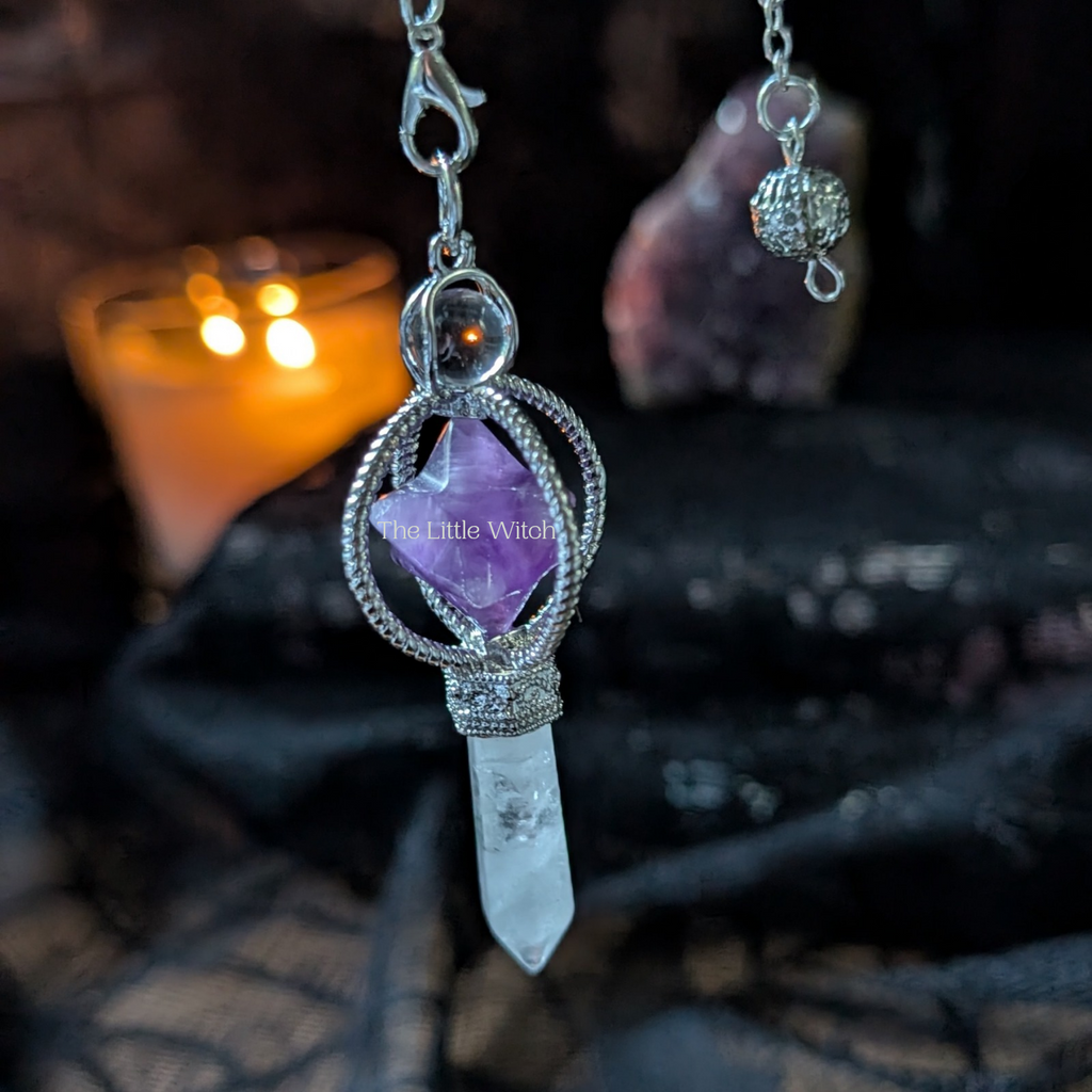 Amethyst merkabah and clear quartz wand pendulum with black lace backdrop and softly lit candle
