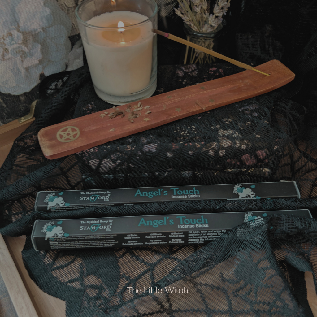 Incense sticks with packaging labeled 'Angel's Touch' on a textured surface with a candle and decorative items.