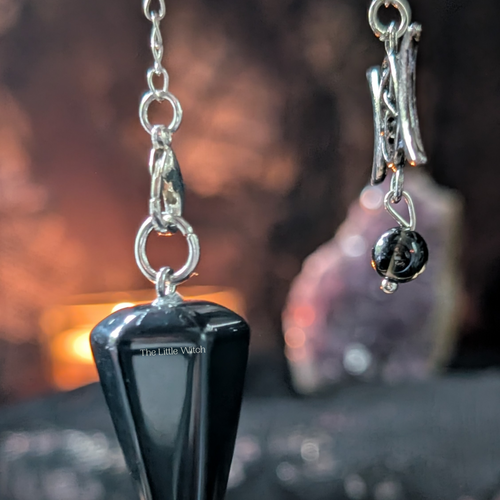 Black pendulum with silver chain against a blurred background