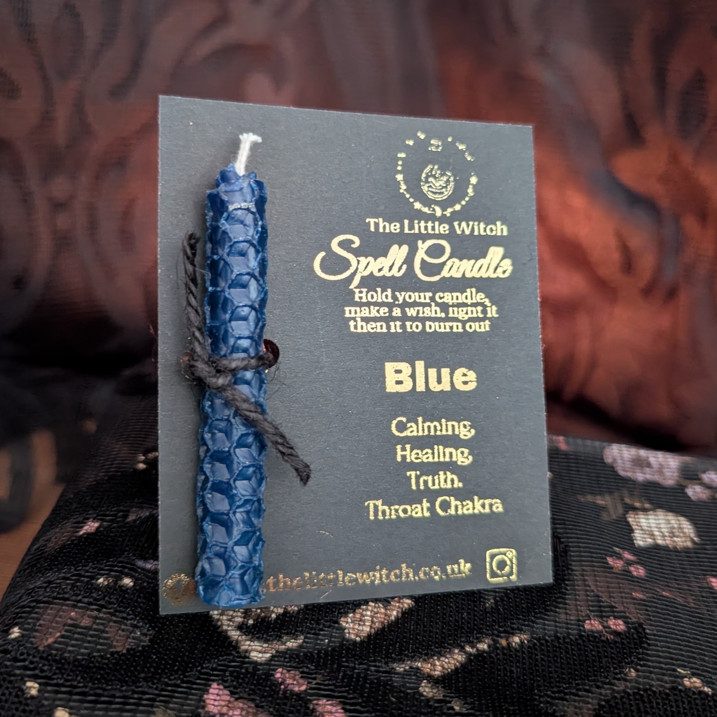 Blue beeswax candle mounted on black card with gold 'The Little witch' branding