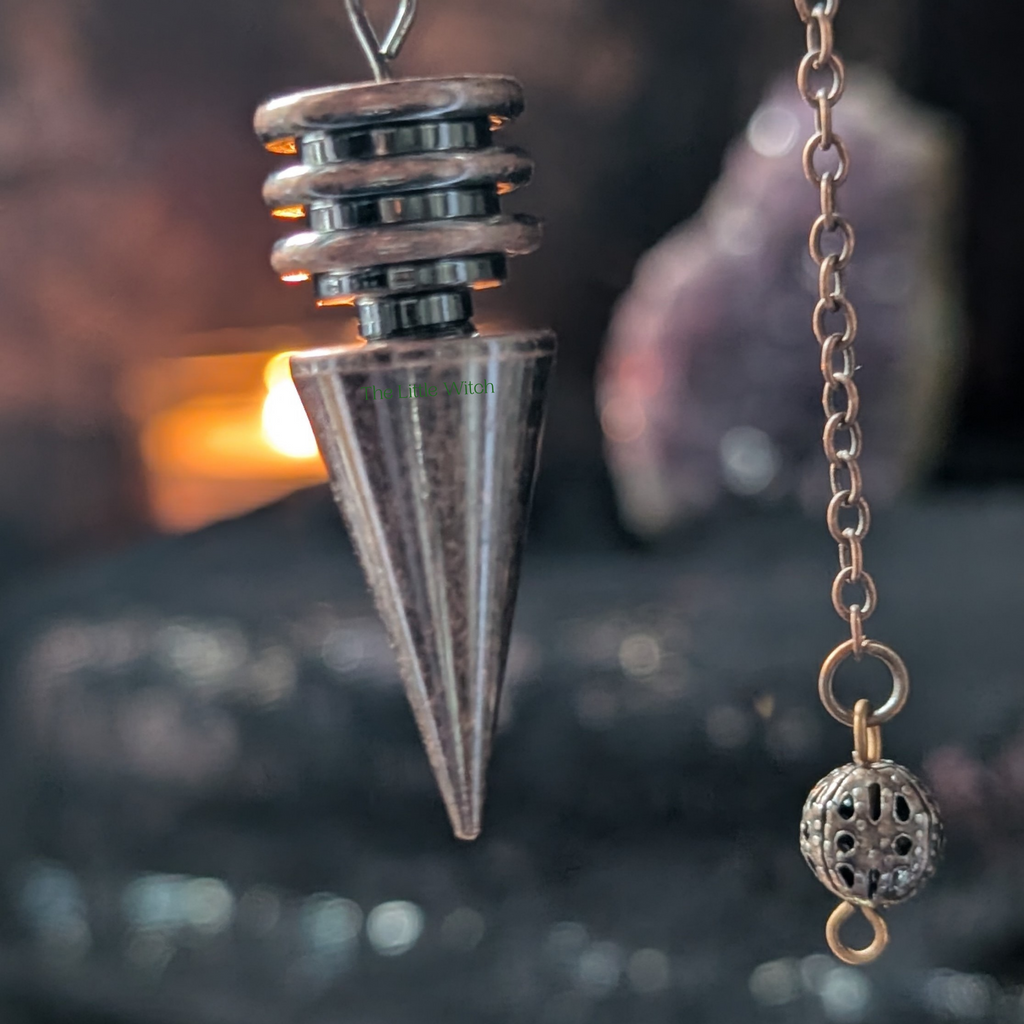 Metallic pendulum with chain against a black lace background