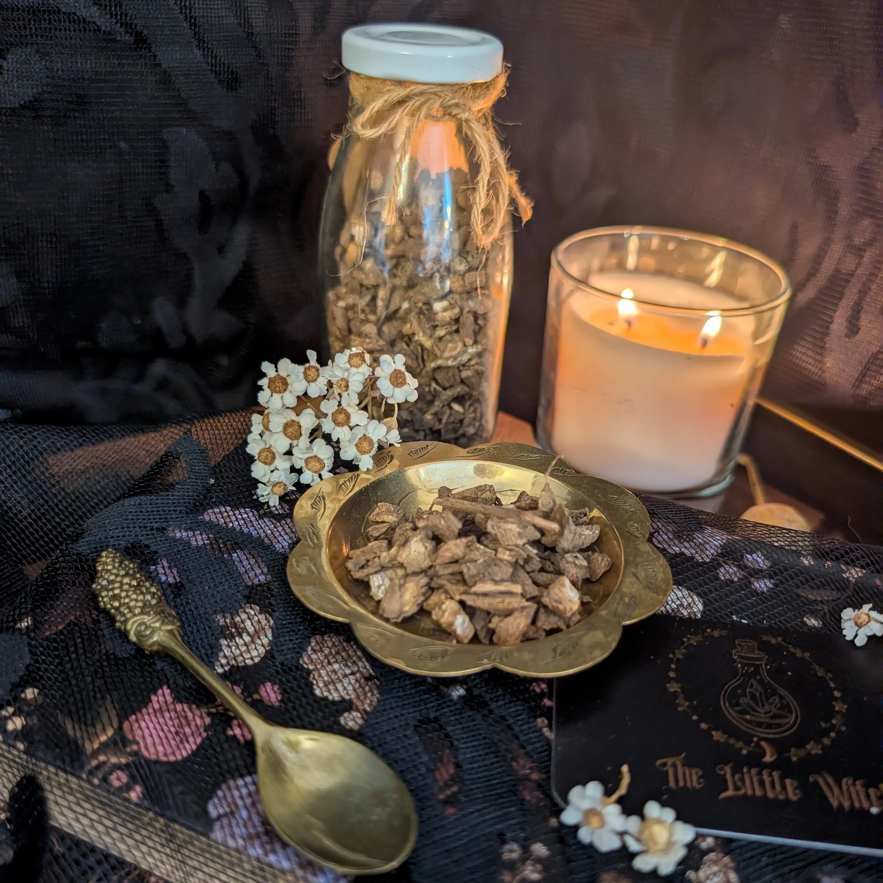 Spices in a bowl with a candle and spoon on a decorative cloth