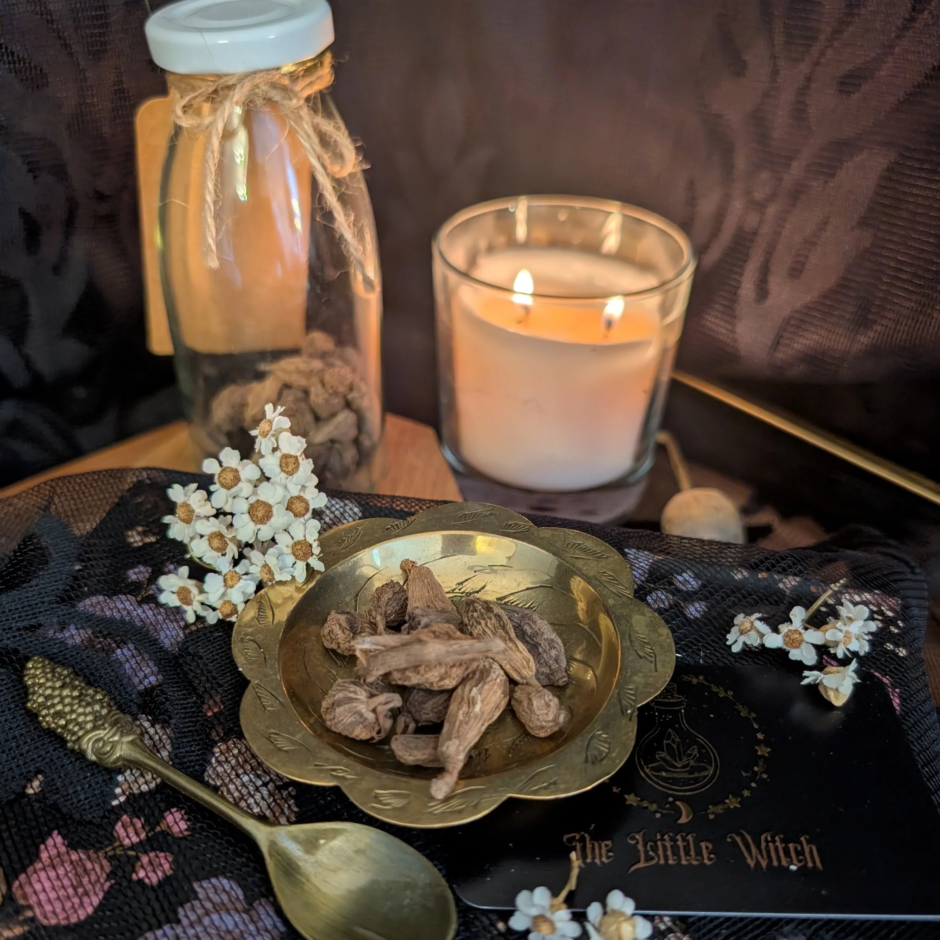 Decorative setup with a candle, jar, and bowl on a dark surface with floral decorations.
