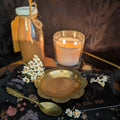 Spice jar, candle, and spoon on a black cloth with floral decorations