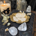 clear quartz crystals in a gold dish sitting upon a black lace cloth with a candle in the background