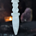 Clear quartz pendulum with black lace background, there is candle light and an amethyst geode also in the background 