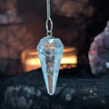 Crystal pendulum on a chain against a black lace cloth and a lit candle