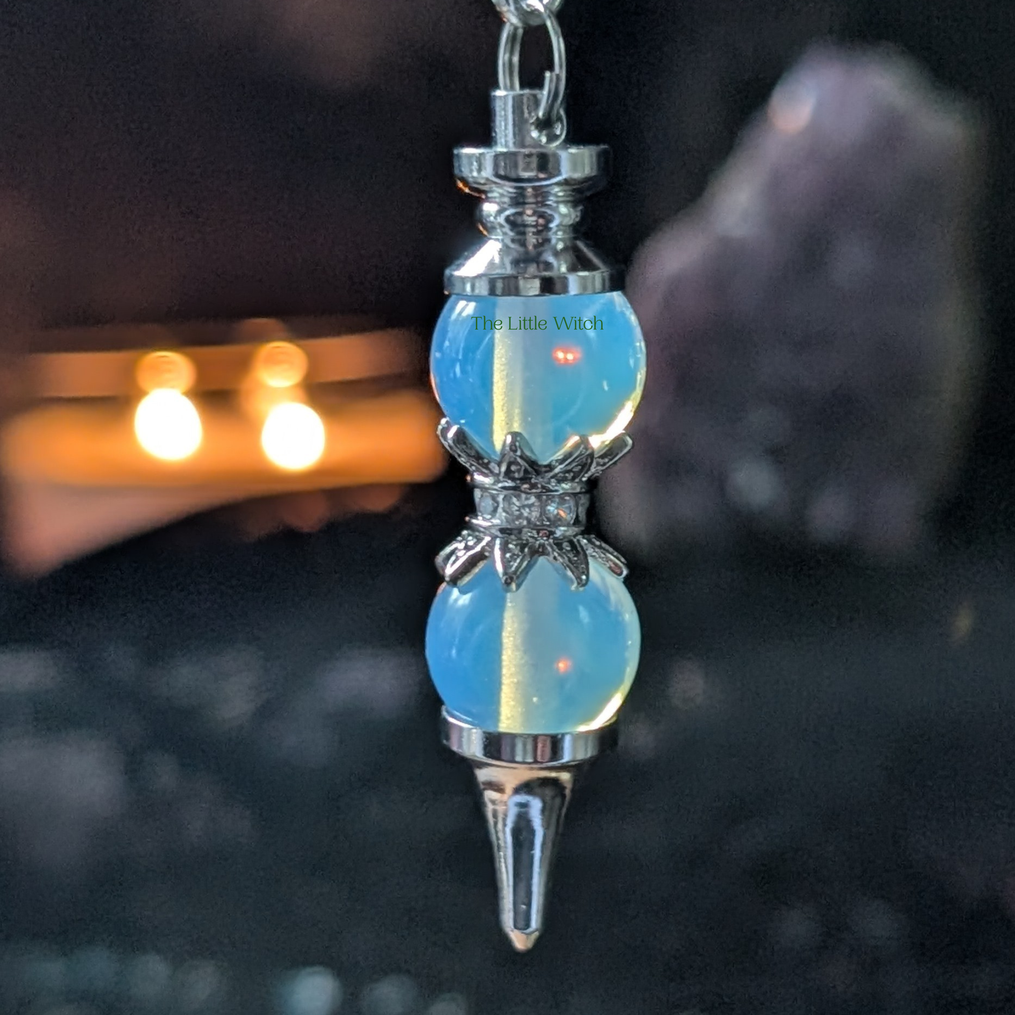 Opalite double pendulum with black lace backdrop and a lit candle with amethyst geode 