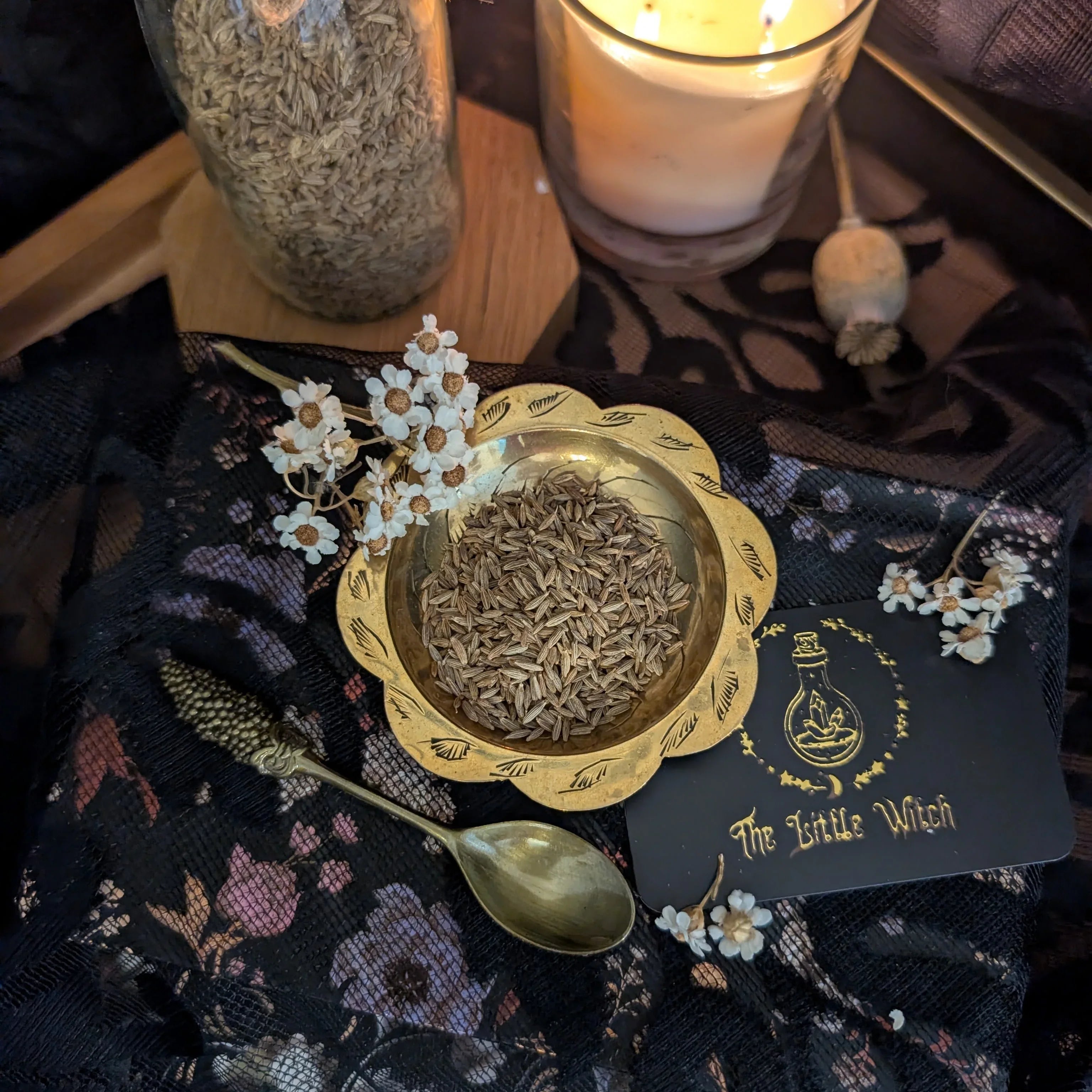 Spices in a bowl with a spoon and decorative card on a patterned surface, likely related to 'The Little Witch'.