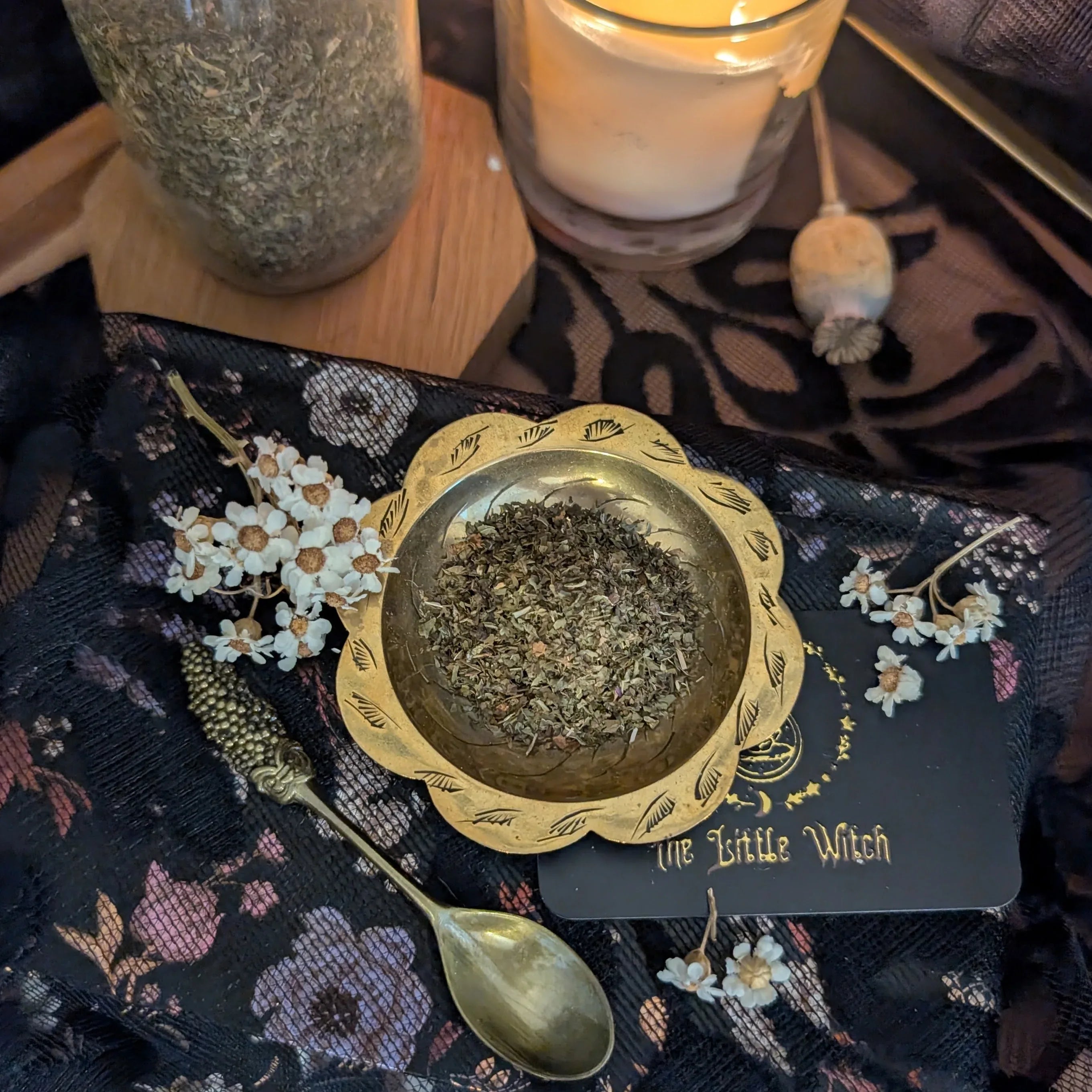 Small brass bowl with mint herbs on a decorative cloth with a candle and jar in the background