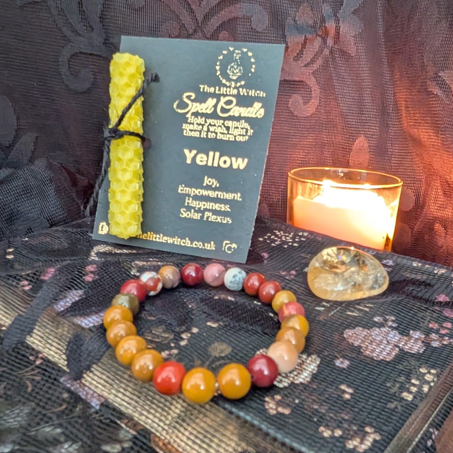 yellow beeswax candle mounted onto The Little Witch branding with a Mookaite bracelet and Citrine tumbled crystal