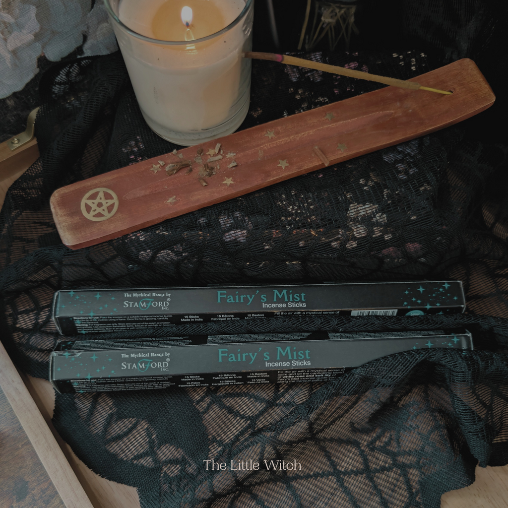 Fairy's Mist incense sticks with a candle and pentacle stick on a black lace background.