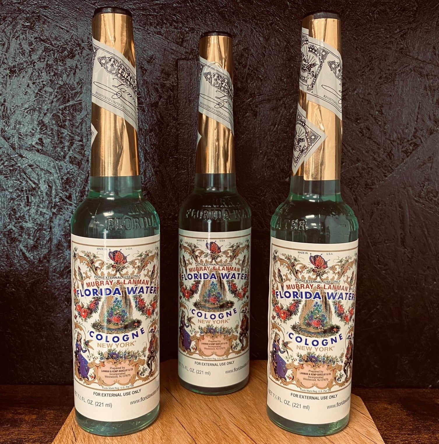 Three bottles of Florida Water cologne with decorative labels on a wooden surface.