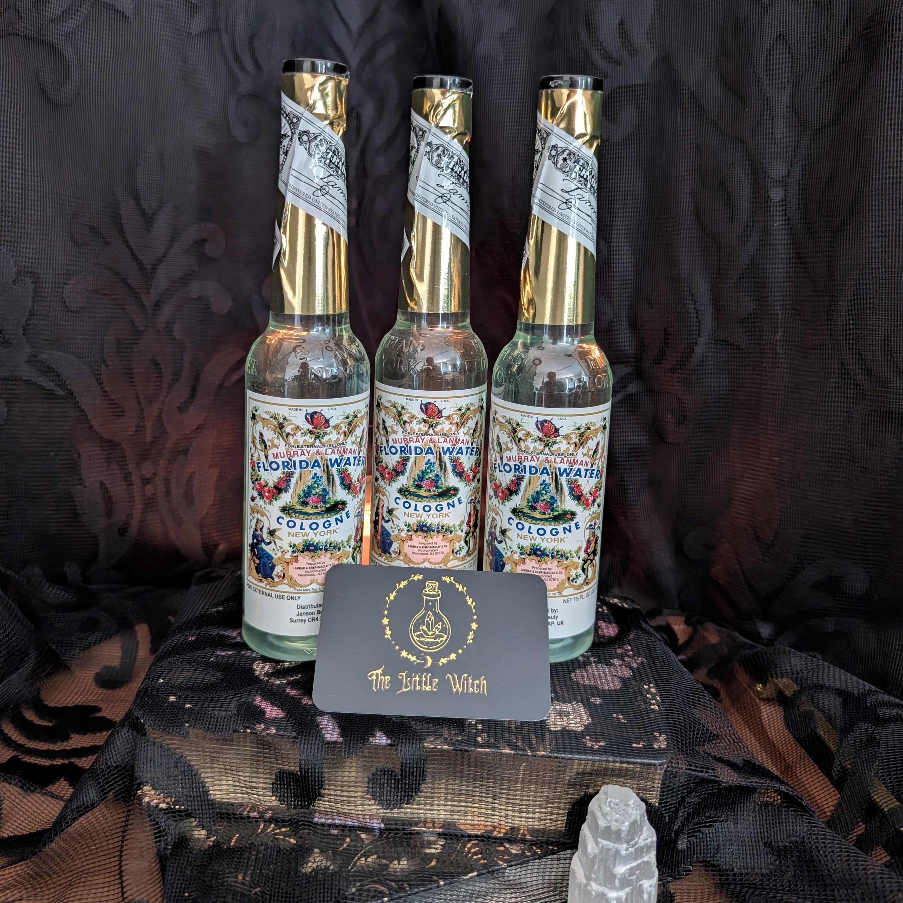 Three bottles of 'Florida Water' with decorative labels on a dark textured surface.
