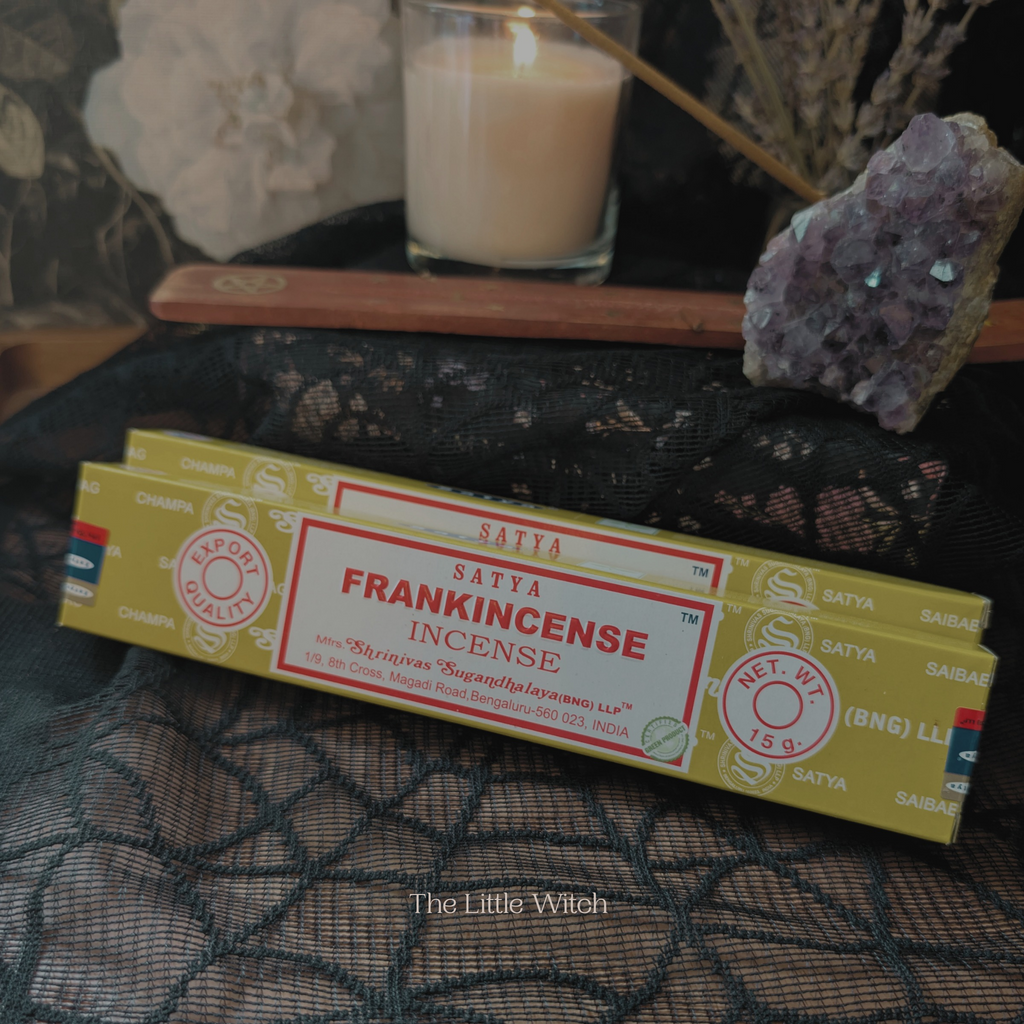 Frankincense incense packaging on a textured surface with a candle and crystals in the background.