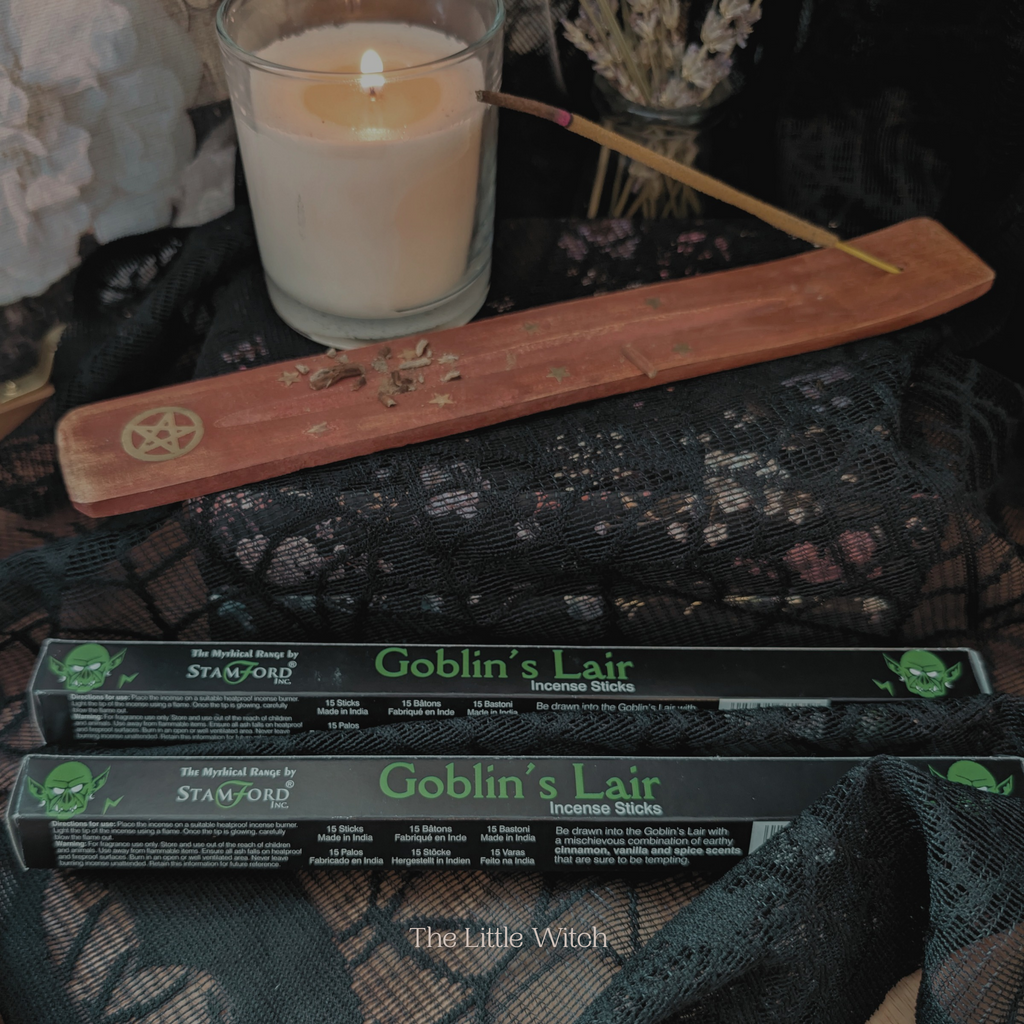 Goblin's Lair incense sticks with a candle and wooden tool on a dark surface