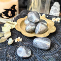Decorative arrangement with Hematite stones in a gold dish on a textured surface.