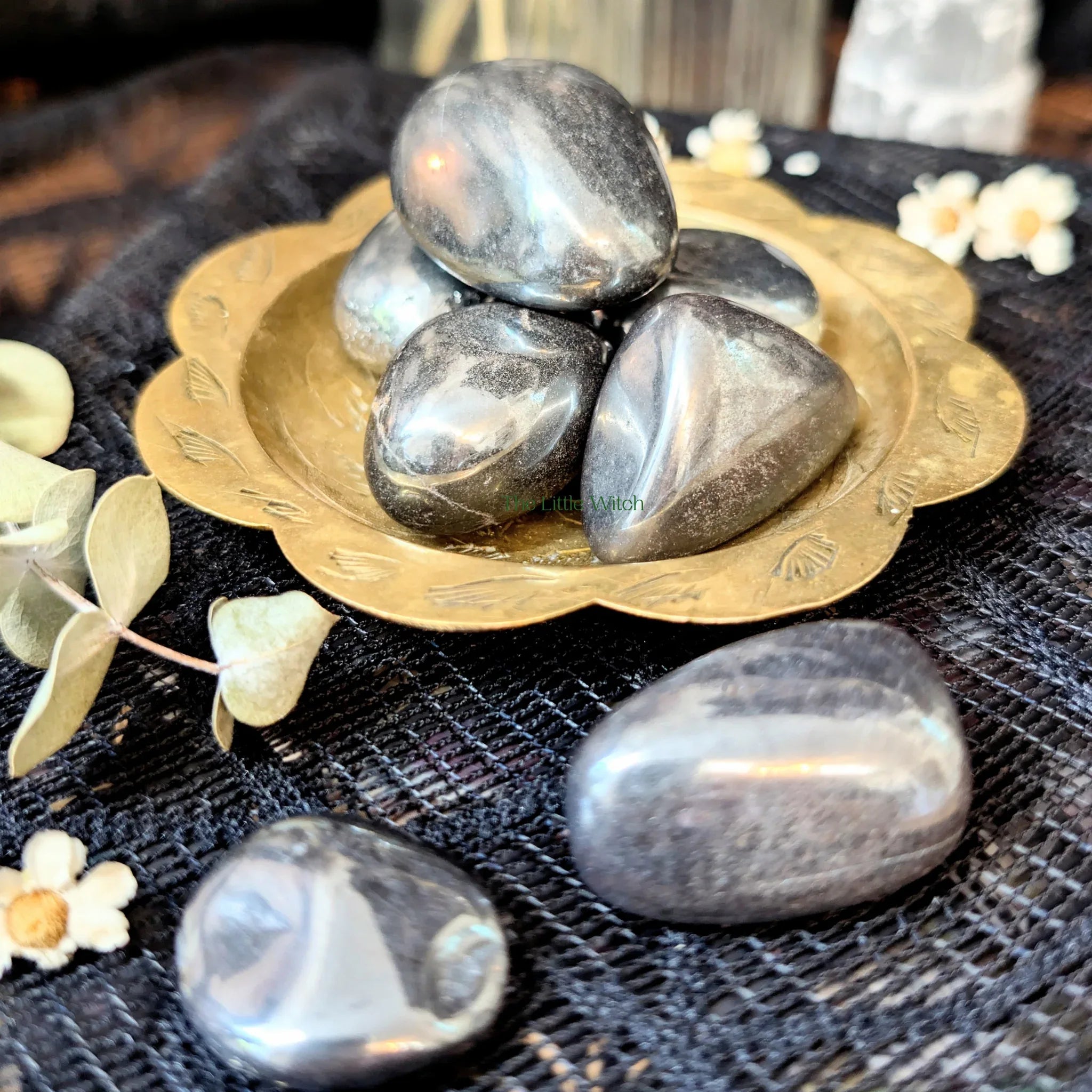 Decorative arrangement of hematite crystals  on a gold dish with flowers on a textured surface