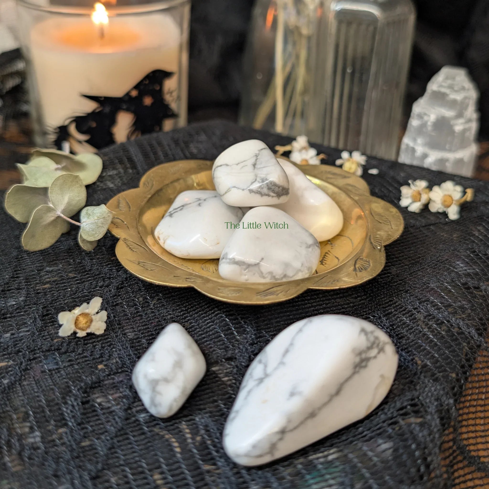 Howlite stones on a brass plate with decorative elements on a dark surface