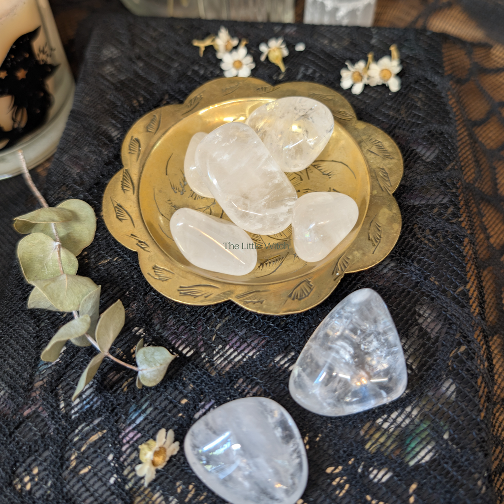 A selection of quartz crystals in an ornate gold bowl sitting upon black lace fabric