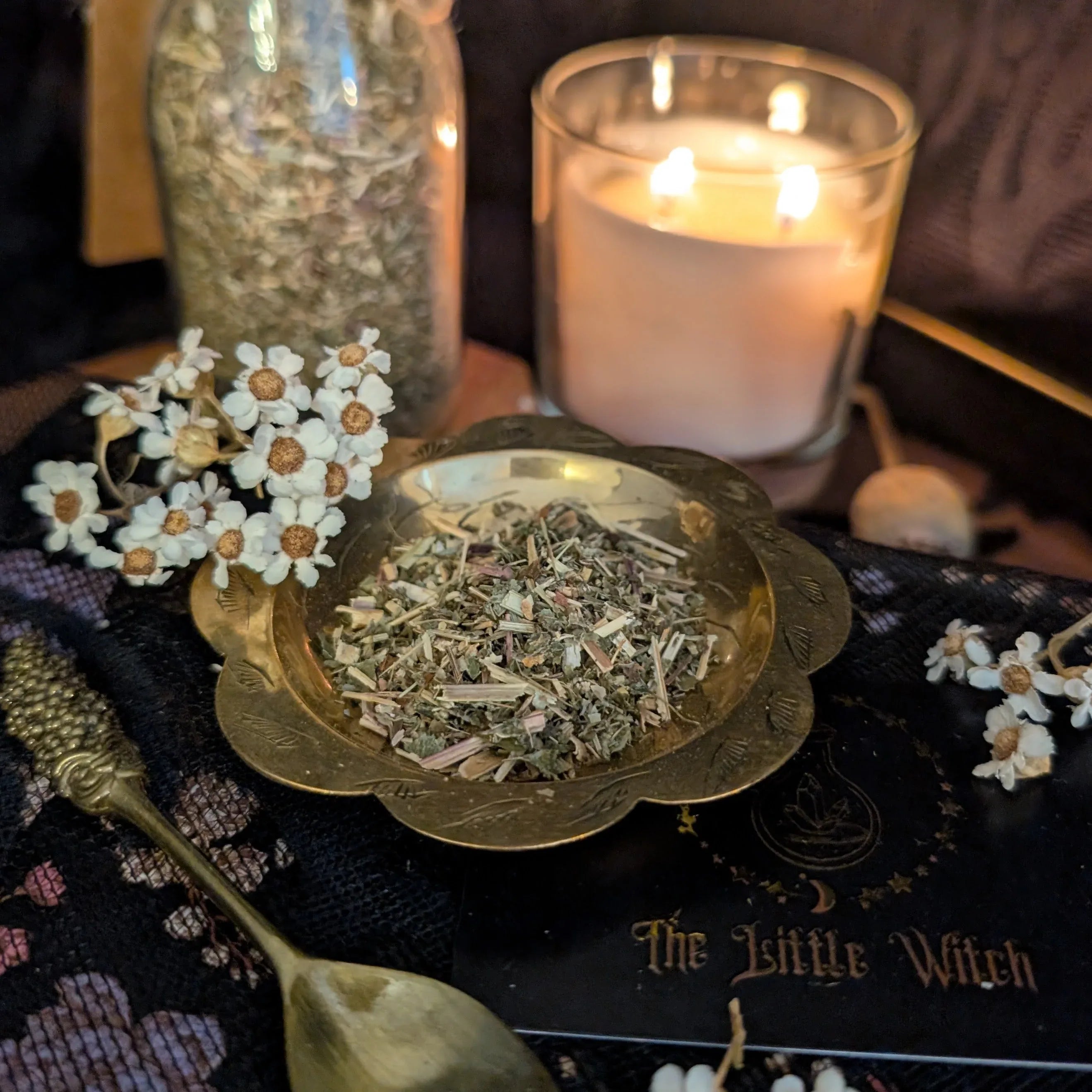 Dried Marjoram in a bowl with a lit candle and decorative elements on a table.