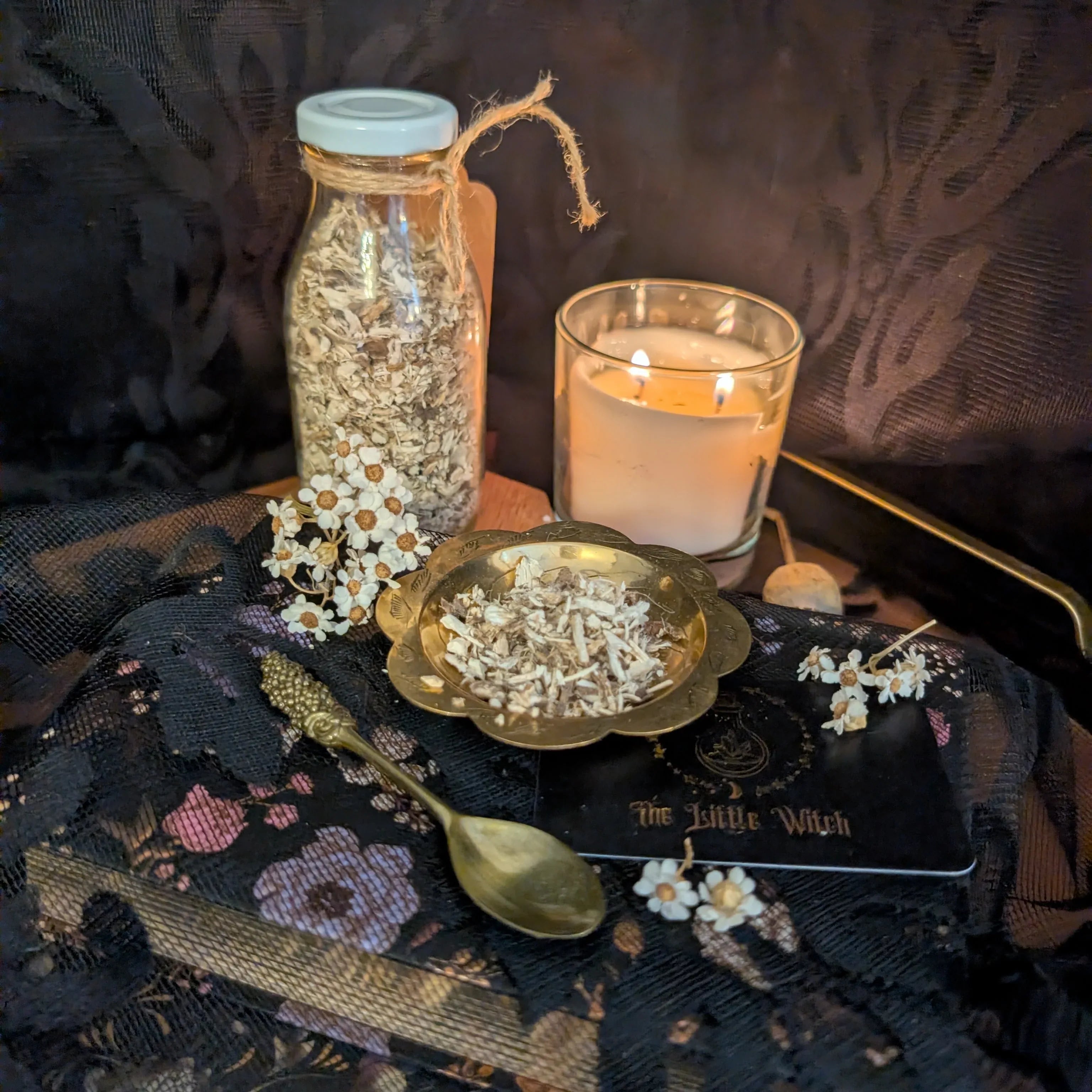 Decorative setup with a candle, jar, and small bowl on a dark fabric surface.