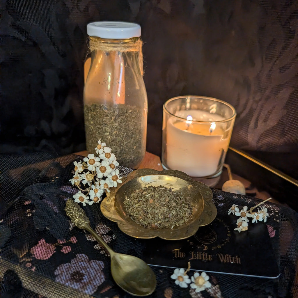 Spice jar, candle, and dried mint on a dark surface with 'The Little Witch' branding.