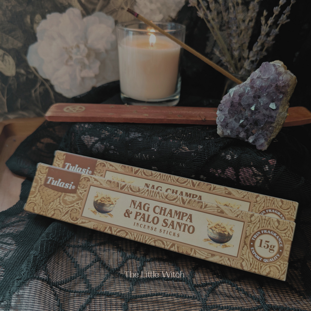 Tulasi Nag Champa & Palo Santo incense sticks with a candle and amethyst crystal on a dark fabric background.