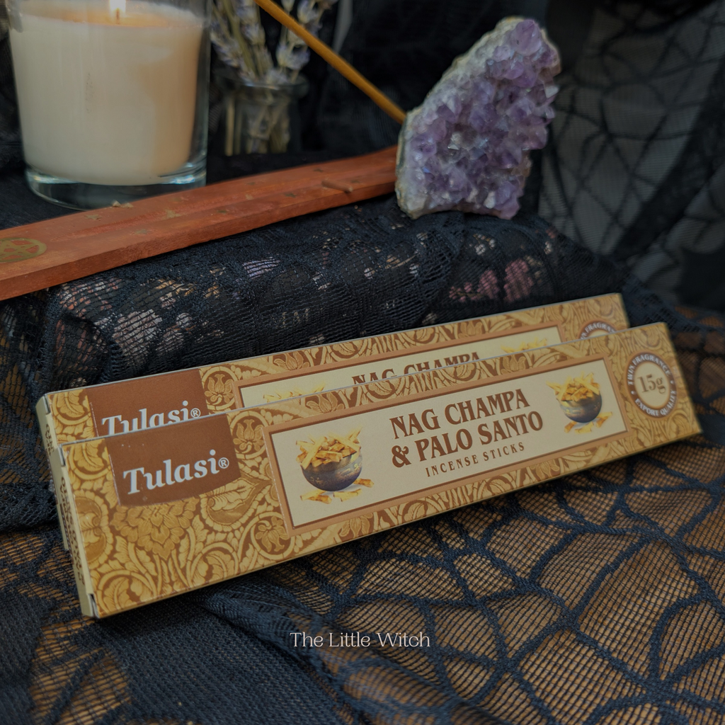 Box of Tulasi Nag Champa & Palo Santo incense sticks on a textured surface with a candle and amethyst crystal in the background.