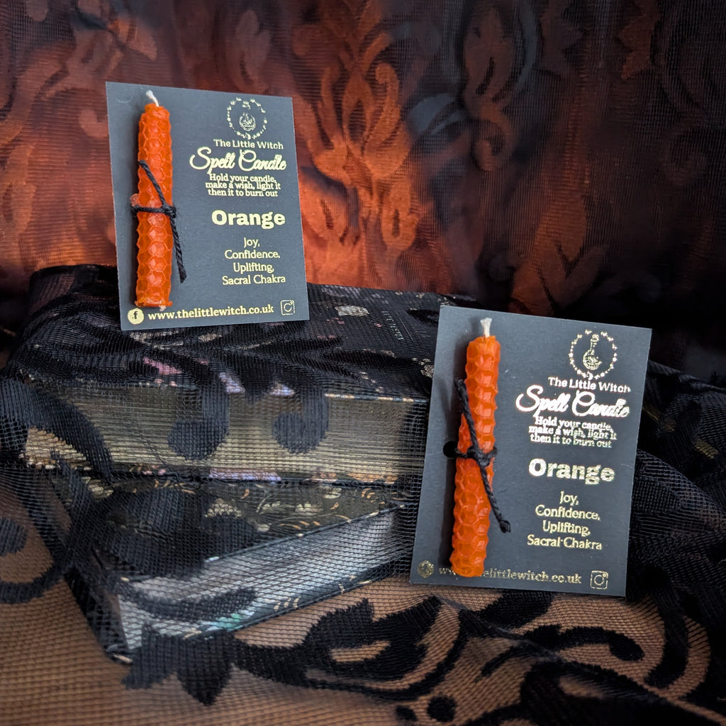 Two orange candles with cards on a patterned fabric background
