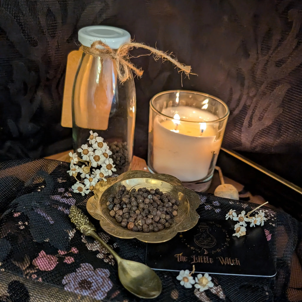 Dried peppercorns in a decorative brass dish upon a dark floral backdrop