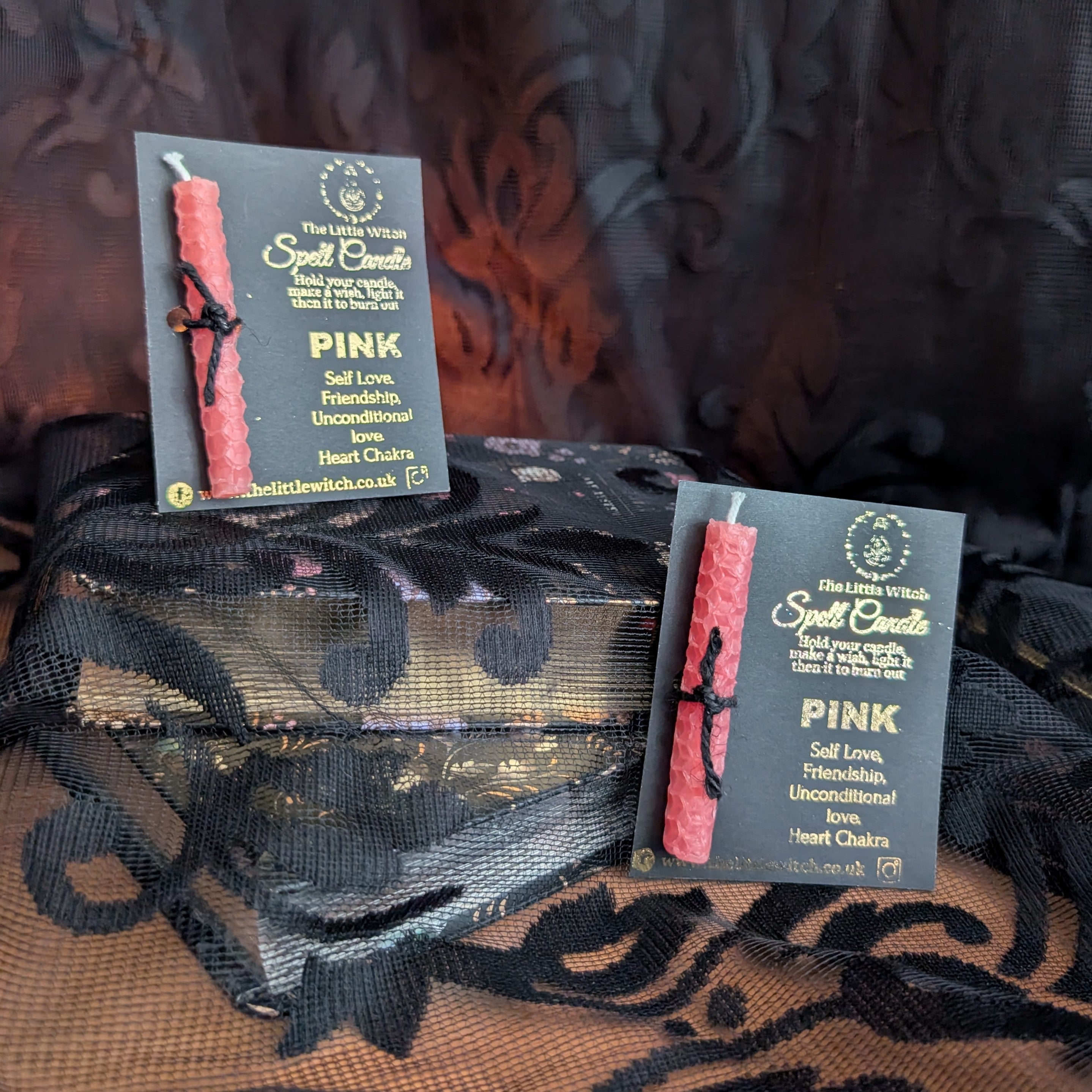 Two pink beeswax candles mounted upon The Little Witch black and gold card