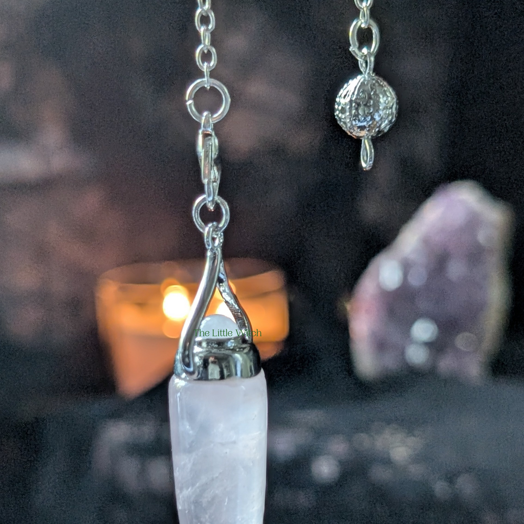 Crystal pendulum with silver chain and  against a dark background