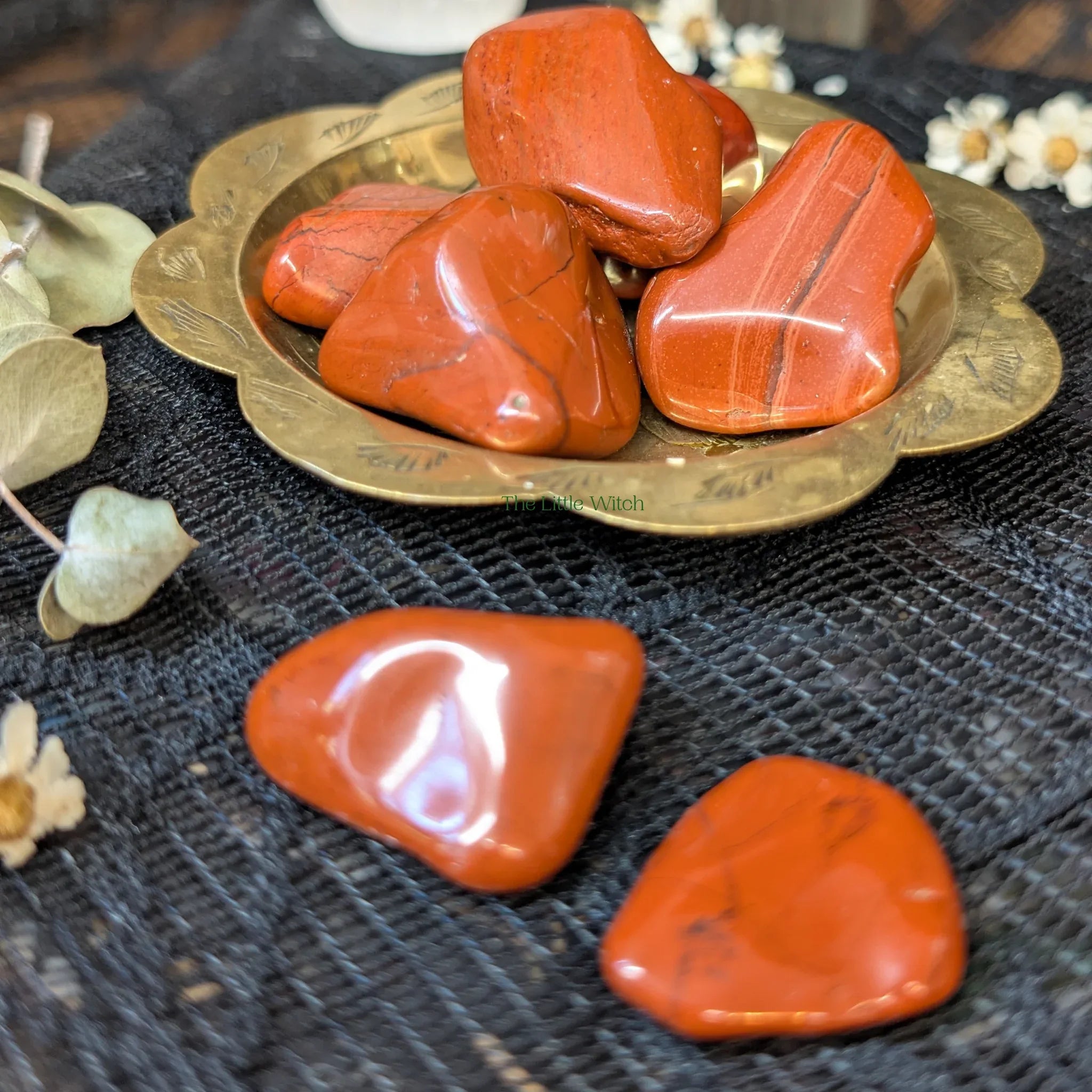 Red Jasper crystals on a brass plate with a dark textured background