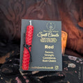 Red spell candle with packaging featuring 'The Little Witch' branding on a dark textured background.