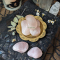 rose quartz in a gold dish on a textured surface with flowers and crystals.