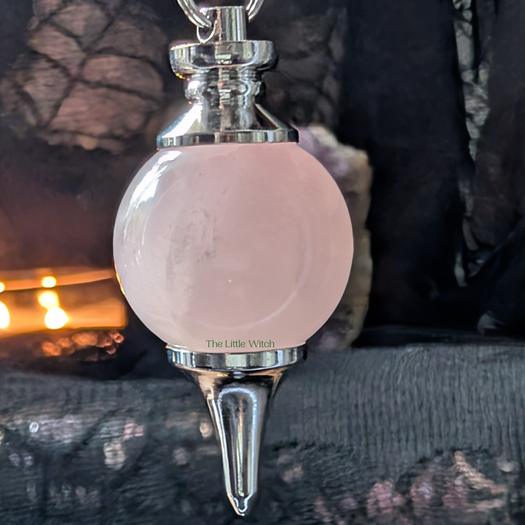 Pink and silver pendulum with 'The Little Witch' branding on a dark background
