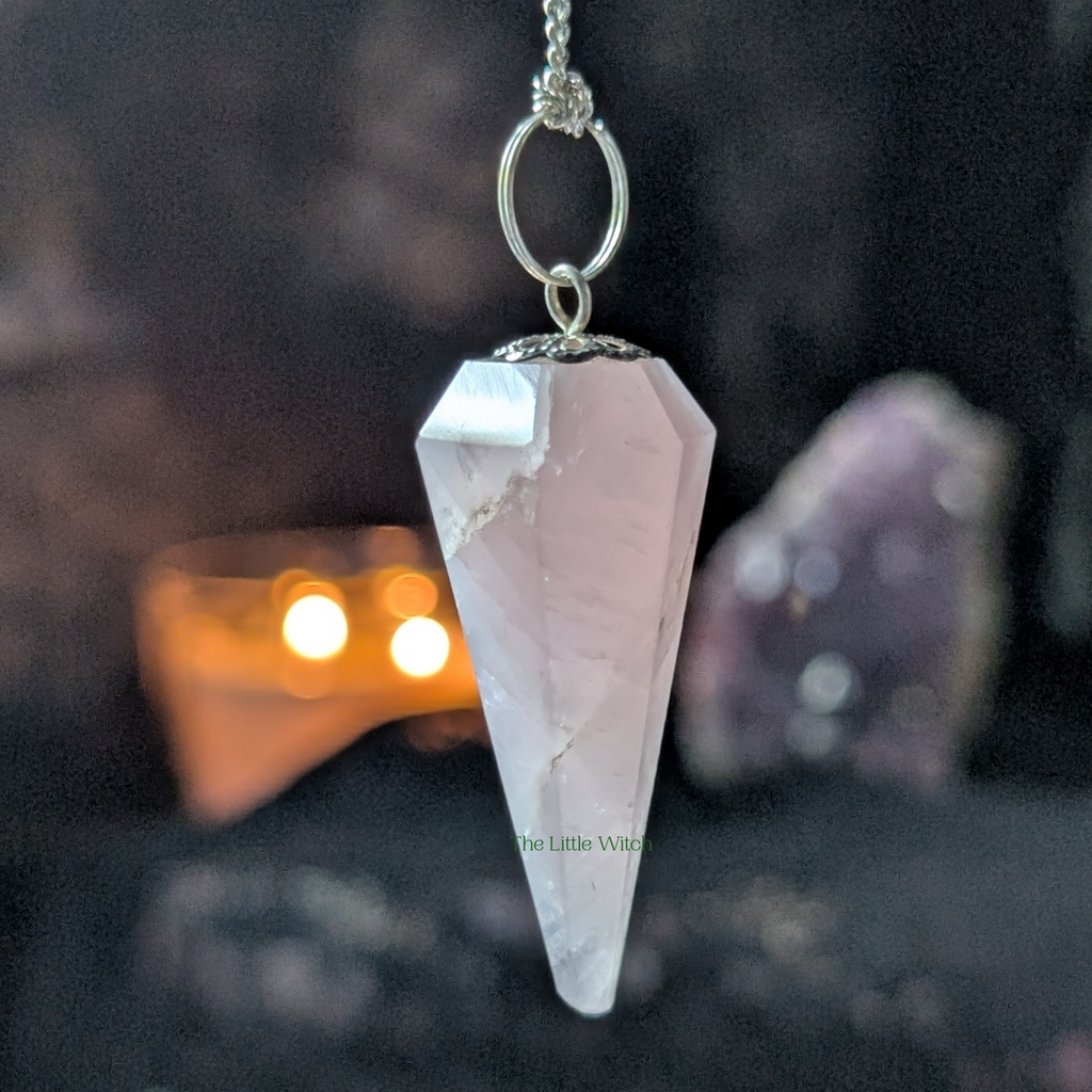 Crystal pendulum on a chain with a blurred background of crystals and lights.