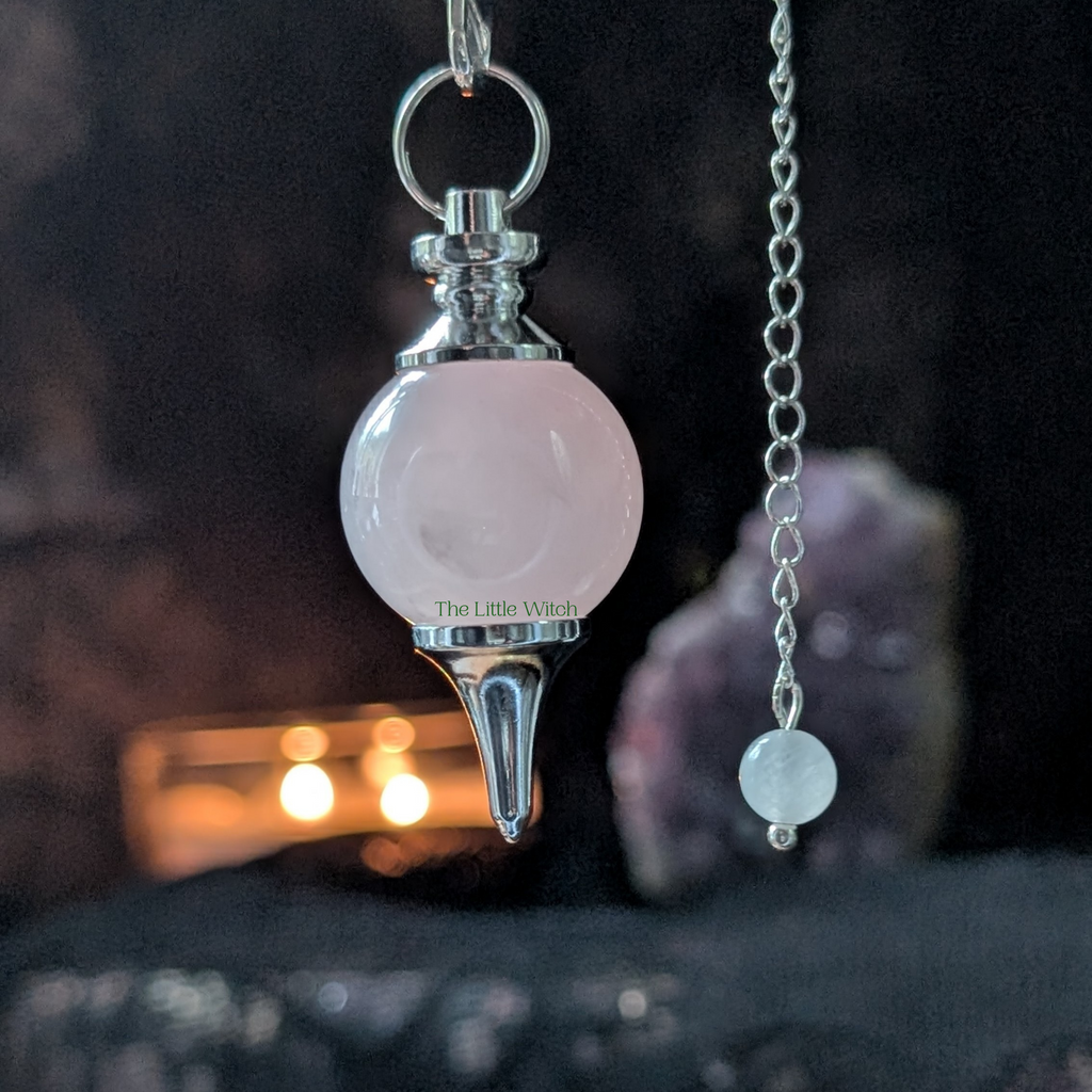 Pink crystal pendulum with chain on a dark background