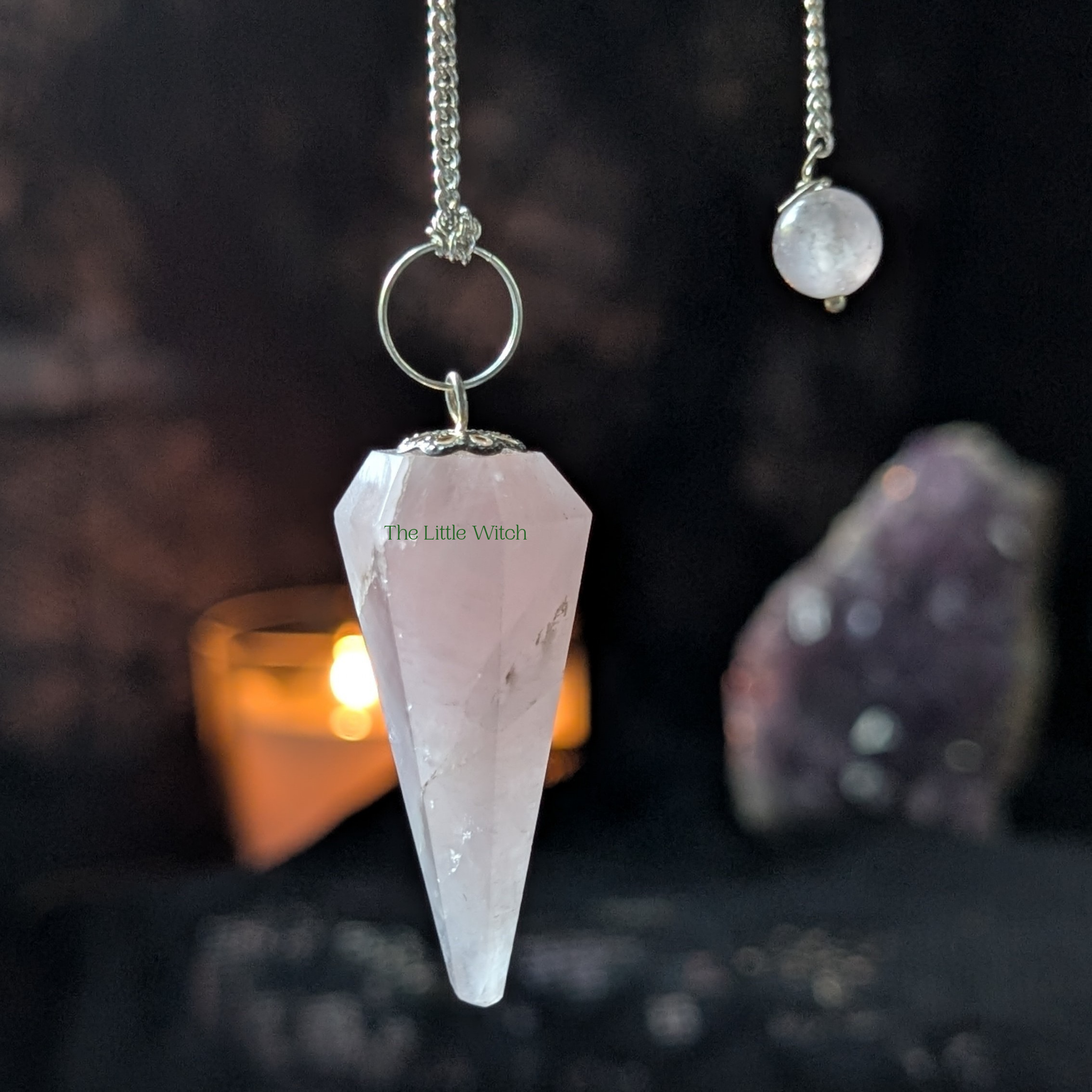 Crystal pendulum with 'The Little Witch' branding on a dark background with crystals and candles.