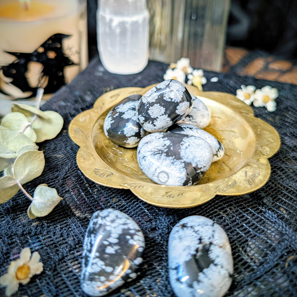 Decorative stones on a gold plate with candles and flowers in the background