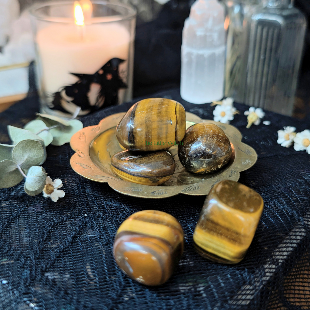 Tiger's eye stones on a decorative plate with candles and flowers in the background