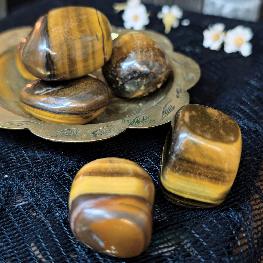 Tiger eye stones on a decorative plate with flowers in the background