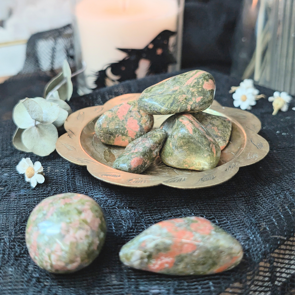 Unakite stones on a decorative plate with a black lace tablecloth and white flowers.