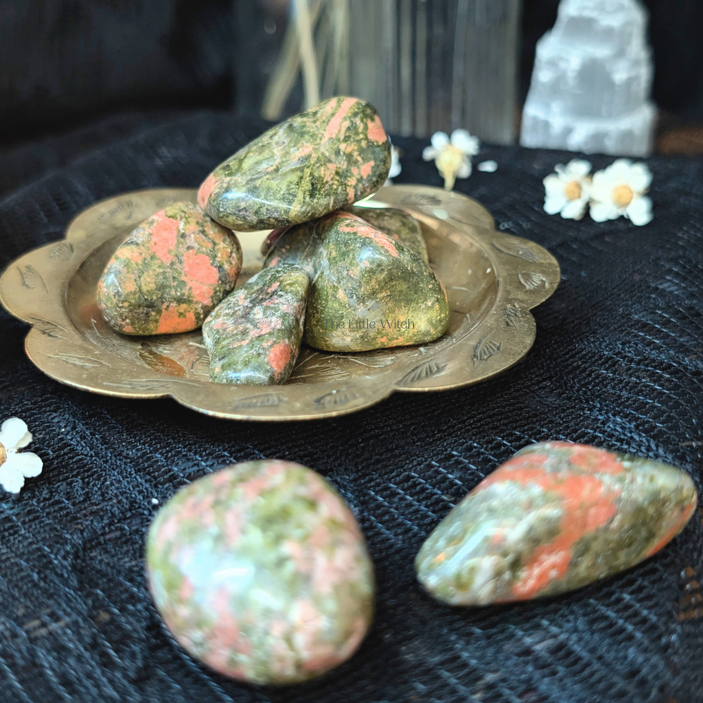 Unakite stones on a brass plate with a dark textured background