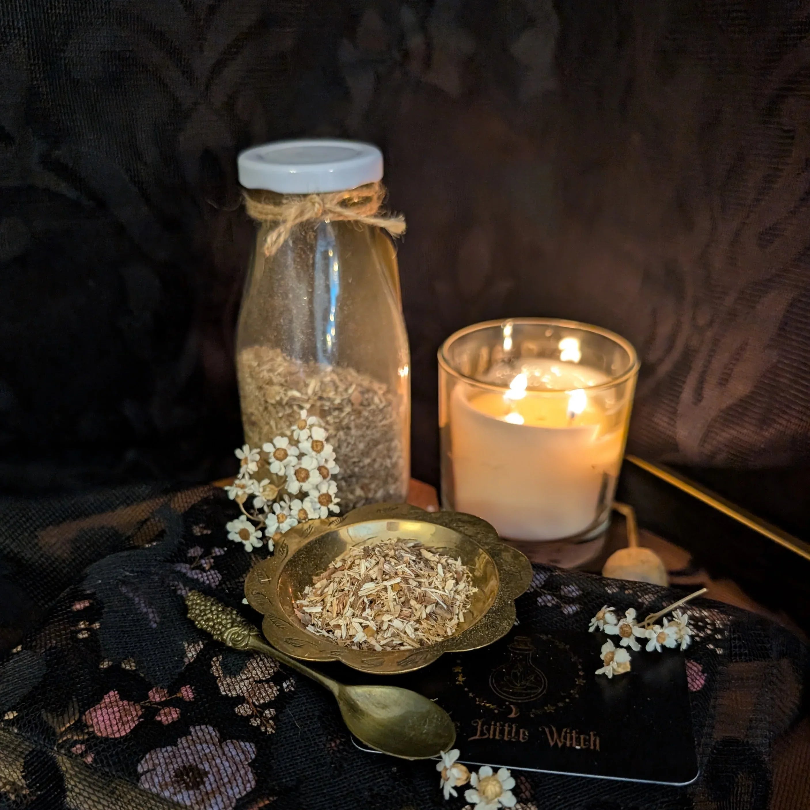 Dried White Willow bark in a gold dish upon a floral backdrop with glowing candlelight