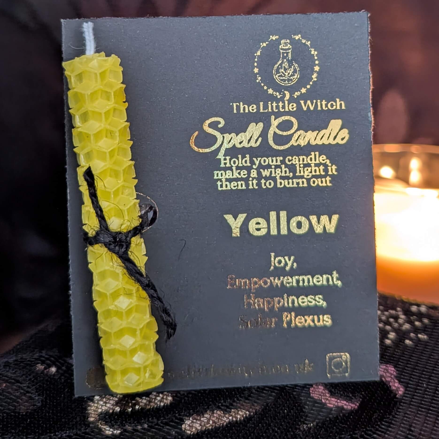 Yellow beeswax candle mounted onto luxury black card with gold The Little Witch foiled branding