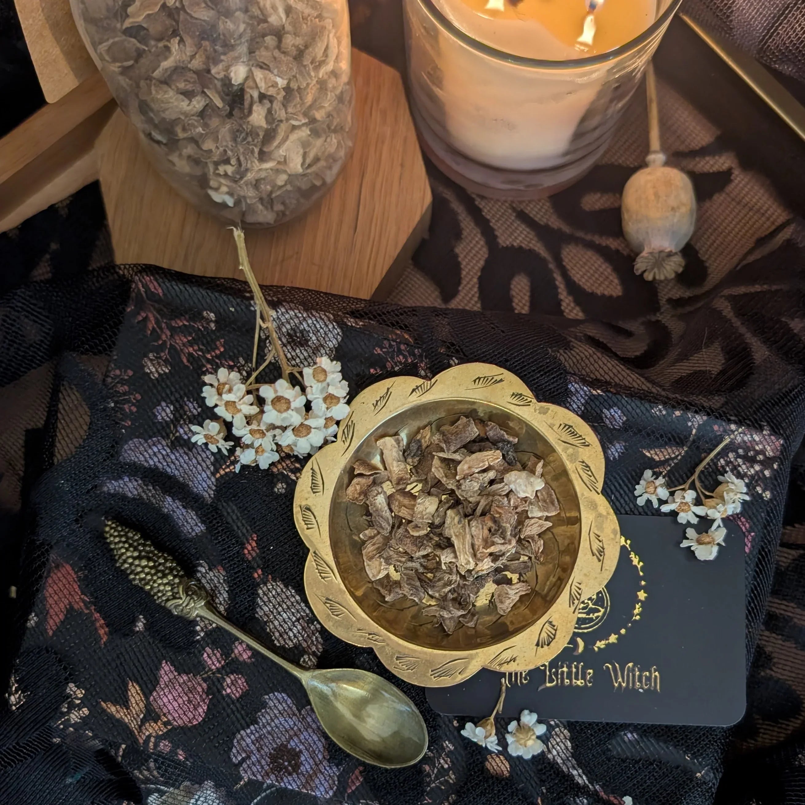 Bowl of dried herbs on a decorative cloth with a candle in the background